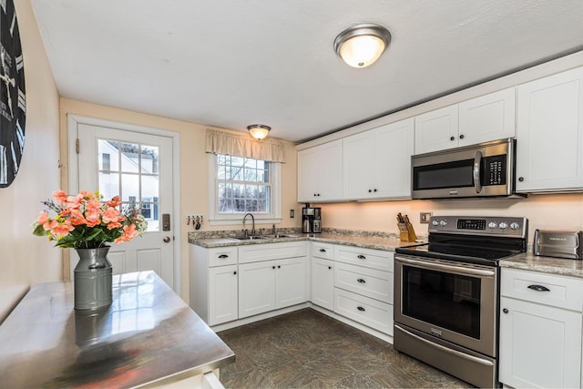 kitchen with light stone counters, sink, white cabinets, and appliances with stainless steel finishes