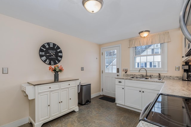 kitchen with white cabinetry, sink, and range