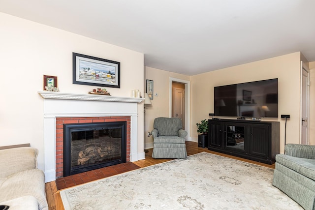 living room featuring wood-type flooring and a brick fireplace