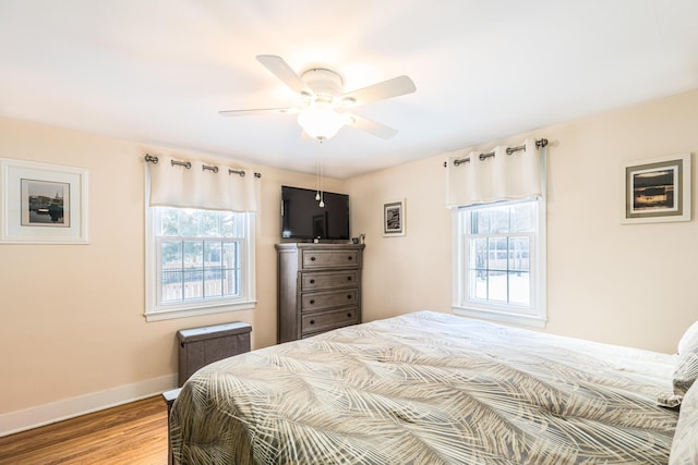 bedroom featuring multiple windows, hardwood / wood-style flooring, and ceiling fan