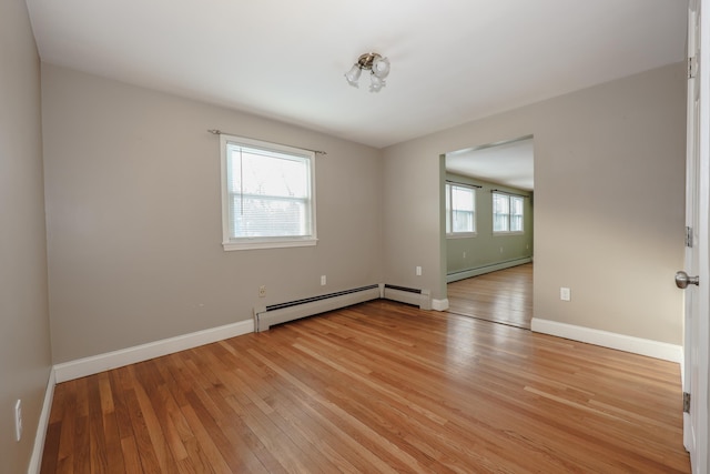 unfurnished room with a baseboard heating unit and light hardwood / wood-style floors