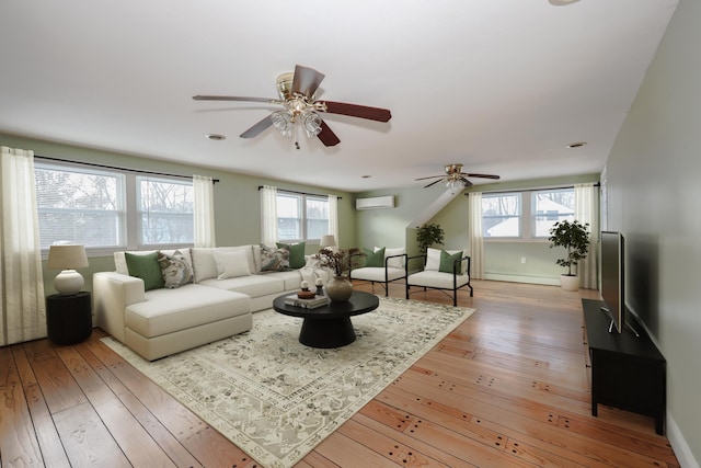 living room with plenty of natural light, light wood-type flooring, a wall mounted air conditioner, and baseboard heating