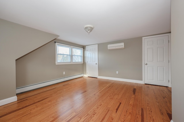 bonus room featuring a baseboard radiator, a wall unit AC, and light wood-type flooring