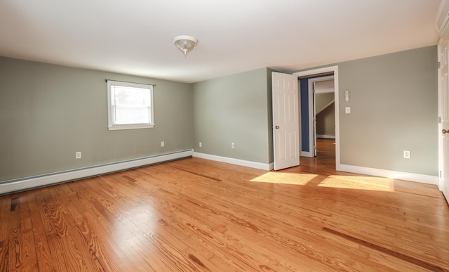 empty room featuring light wood-type flooring and a baseboard heating unit