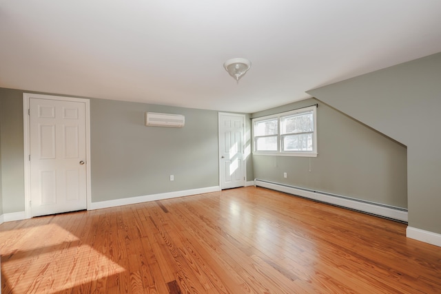 bonus room with a wall mounted AC, light wood-type flooring, and a baseboard heating unit