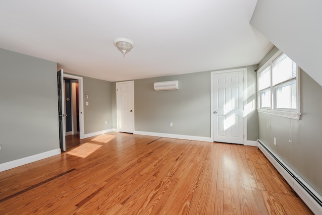 interior space with a baseboard heating unit, light hardwood / wood-style flooring, and a wall unit AC