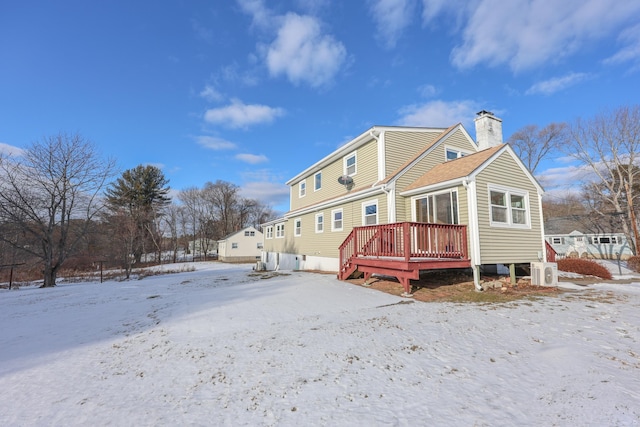 snow covered back of property with a wooden deck and ac unit