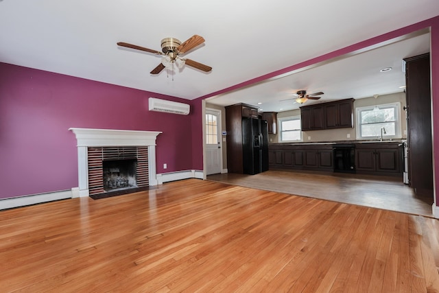 unfurnished living room featuring a baseboard radiator, a fireplace, light hardwood / wood-style flooring, and an AC wall unit