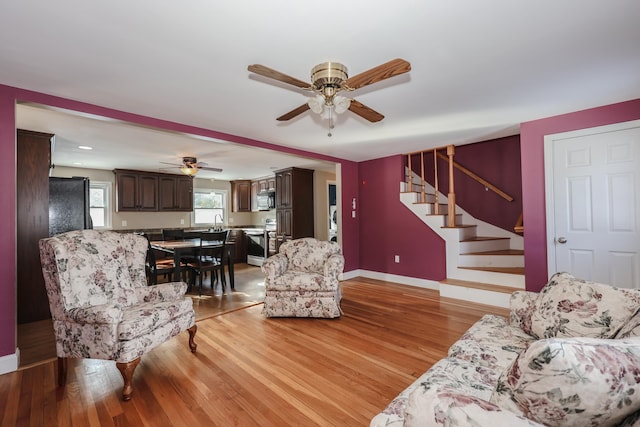 living room with sink, light hardwood / wood-style floors, and ceiling fan