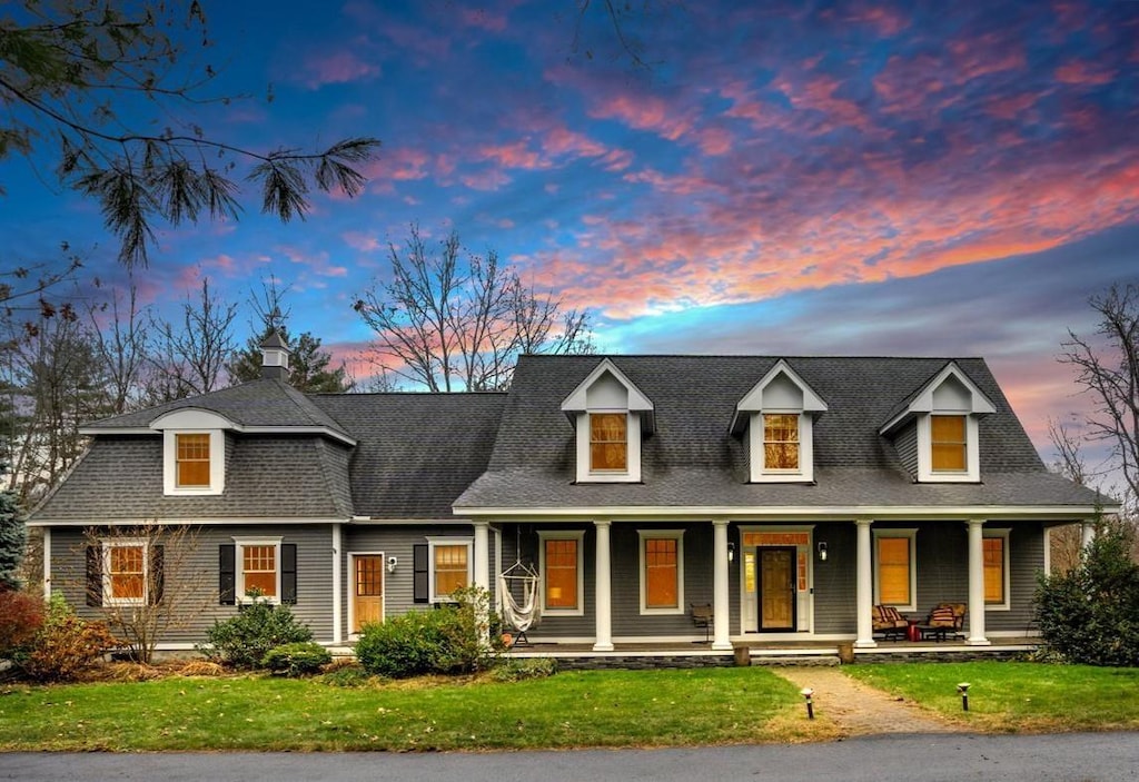 cape cod house with covered porch and a lawn