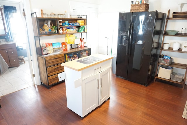 kitchen featuring black fridge, a center island, white cabinets, and dark hardwood / wood-style flooring