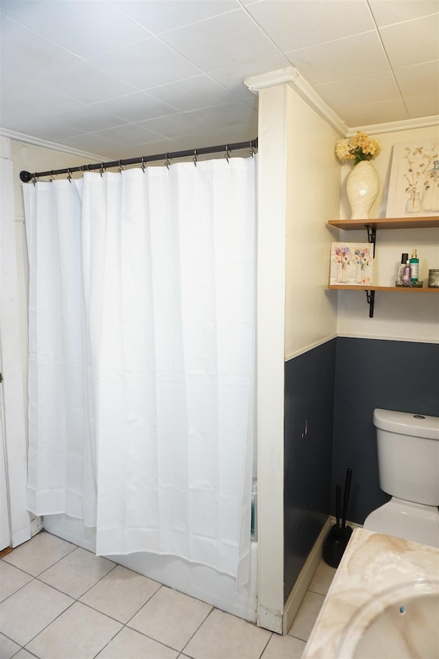 bathroom featuring tile patterned flooring, crown molding, toilet, and walk in shower