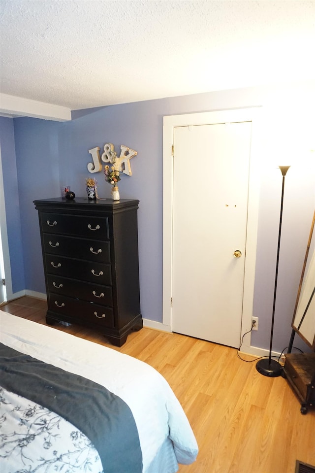 bedroom featuring wood-type flooring, a textured ceiling, and a closet