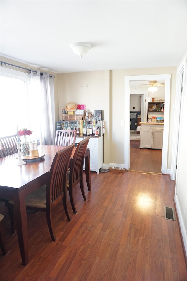 dining area with dark wood-type flooring and ceiling fan