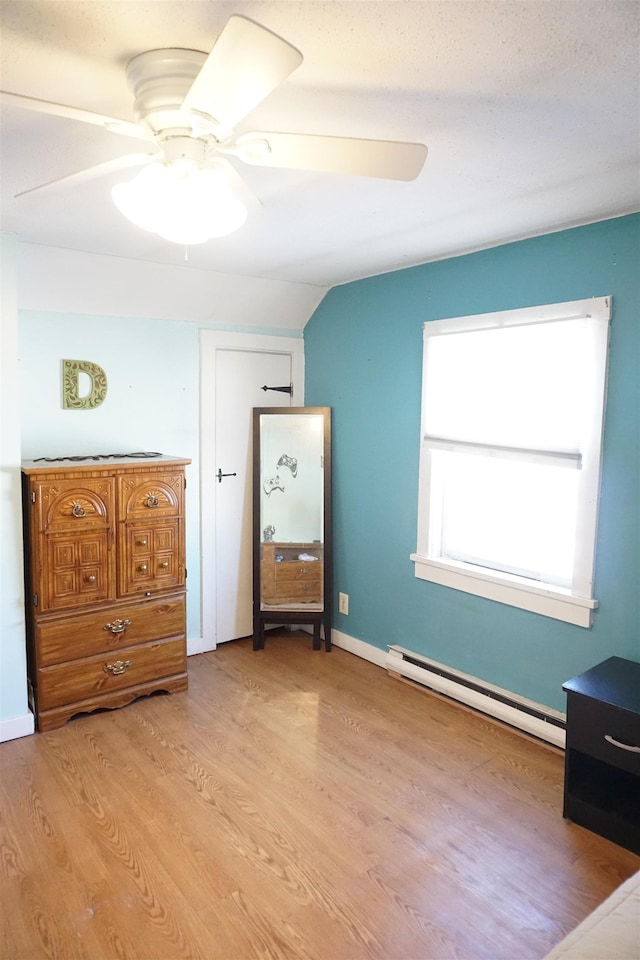 unfurnished bedroom featuring a baseboard heating unit, vaulted ceiling, light hardwood / wood-style floors, and ceiling fan