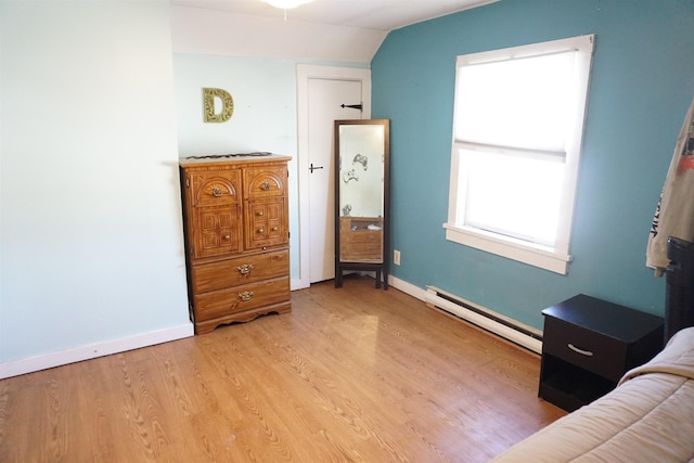 bedroom featuring a baseboard radiator, vaulted ceiling, and light wood-type flooring