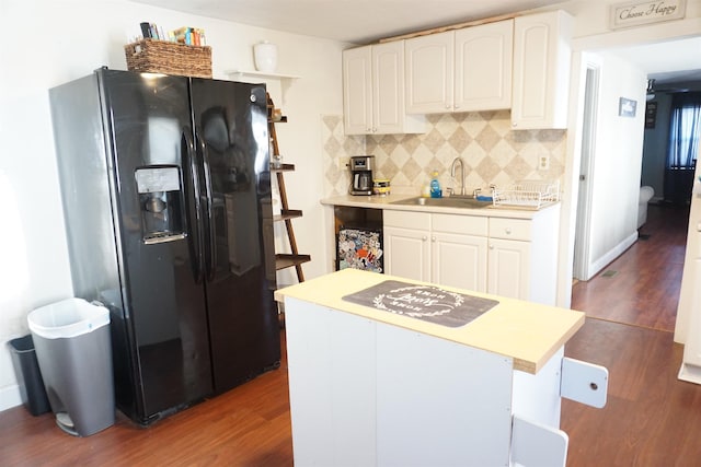 kitchen featuring white cabinetry, sink, backsplash, dark hardwood / wood-style flooring, and black fridge