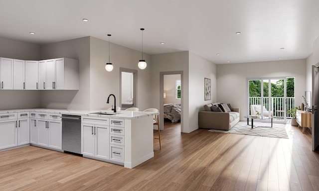 kitchen featuring a peninsula, open floor plan, light wood finished floors, and a sink