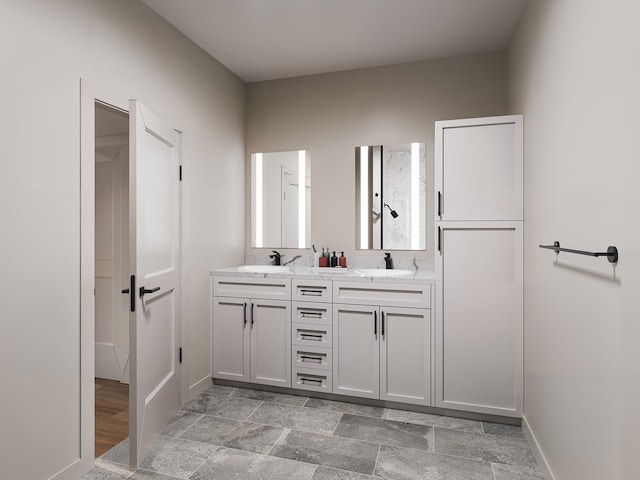 bathroom featuring double vanity, baseboards, and a sink