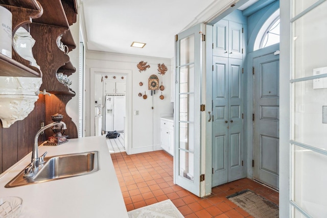 kitchen with white cabinetry, sink, crown molding, and light tile patterned floors