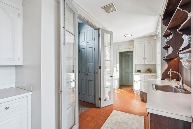 kitchen with sink, light tile patterned floors, and white cabinets