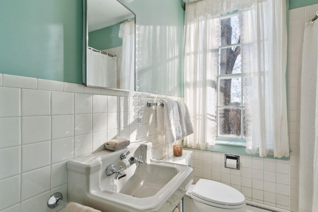 bathroom featuring a baseboard radiator, sink, tile walls, and toilet