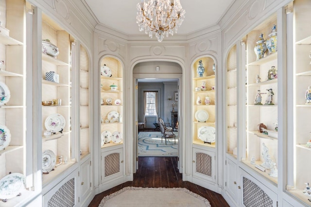 hallway featuring a notable chandelier, dark hardwood / wood-style floors, and built in features