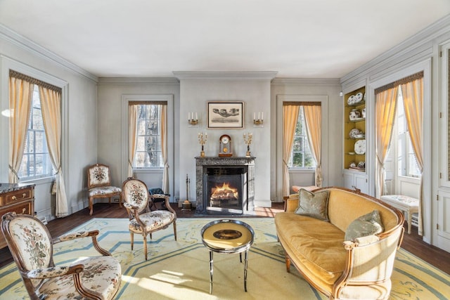 living area with wood-type flooring, ornamental molding, and a wealth of natural light