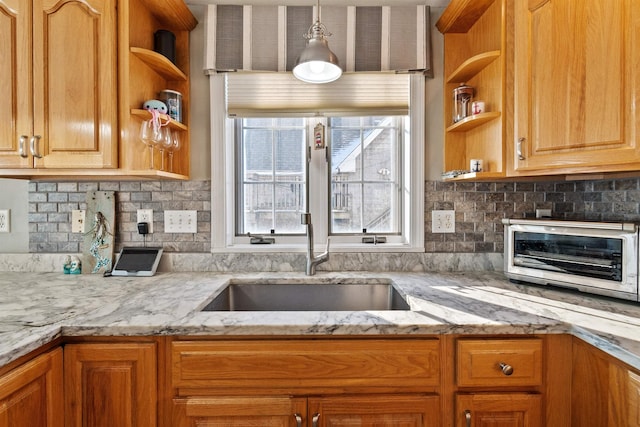 kitchen featuring tasteful backsplash, decorative light fixtures, and light stone countertops