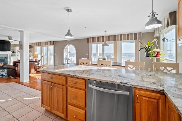 kitchen with pendant lighting, light tile patterned floors, light stone countertops, and dishwasher