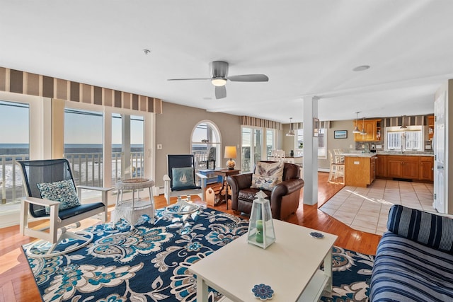 living room with ceiling fan, light wood-type flooring, and a wealth of natural light