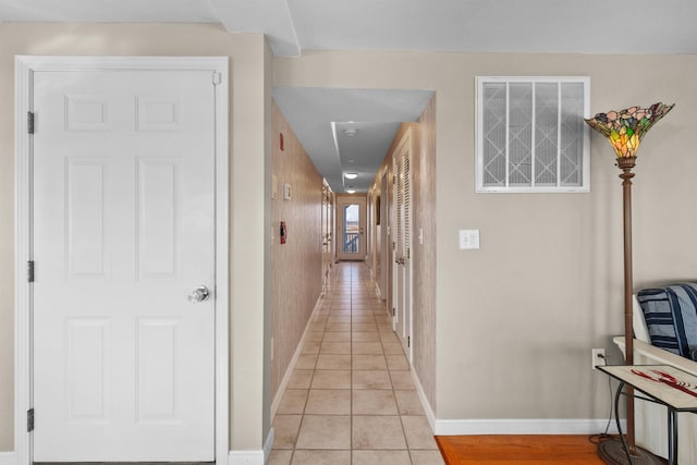 hall featuring wooden walls and light tile patterned floors