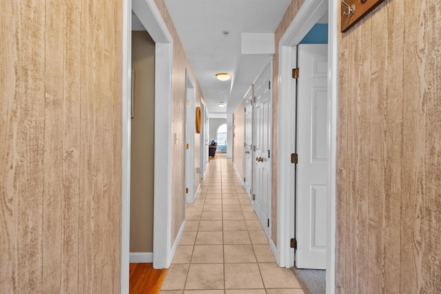 corridor with light tile patterned floors and wooden walls