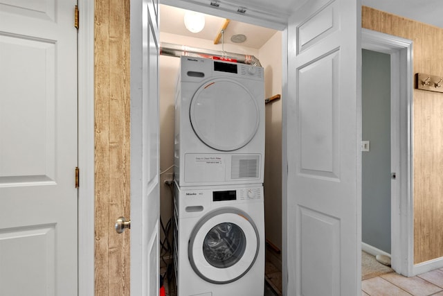 laundry room with stacked washing maching and dryer and light tile patterned floors