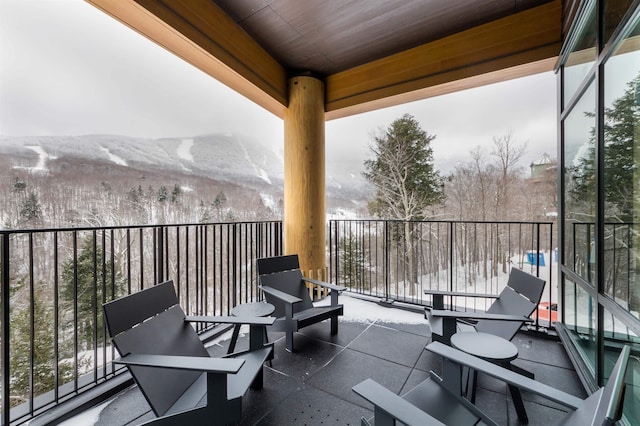 snow covered back of property featuring a mountain view