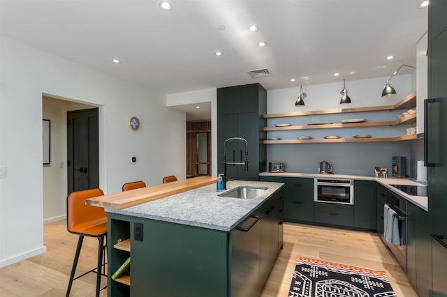 kitchen featuring light hardwood / wood-style floors, sink, a kitchen breakfast bar, and an island with sink