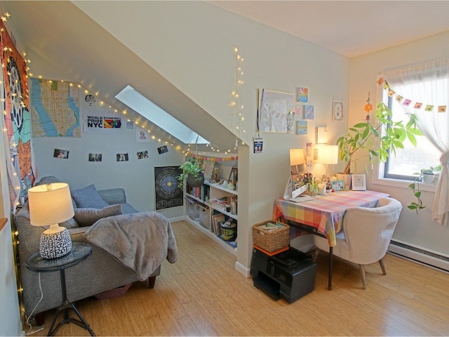 bedroom featuring a baseboard heating unit, light hardwood / wood-style floors, and a skylight