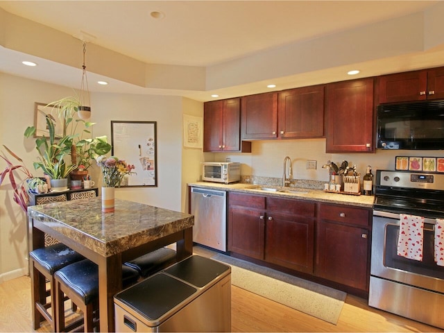 kitchen featuring a kitchen bar, sink, a center island, light wood-type flooring, and stainless steel appliances