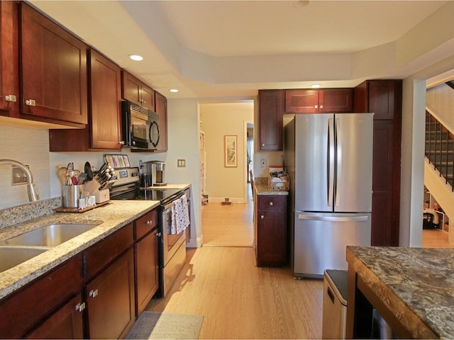 kitchen featuring light stone counters, sink, light hardwood / wood-style floors, and appliances with stainless steel finishes