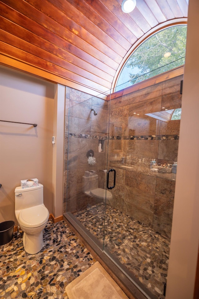 bathroom featuring a shower with door and toilet