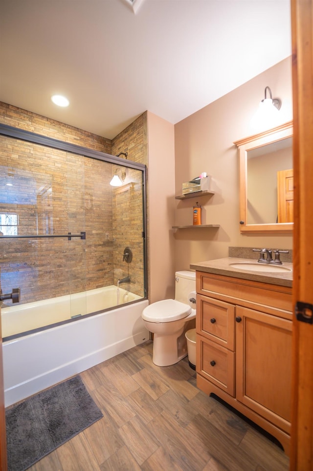 full bathroom with enclosed tub / shower combo, hardwood / wood-style floors, vanity, and toilet