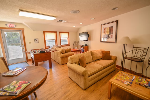 living room featuring vaulted ceiling, a textured ceiling, and light wood-type flooring