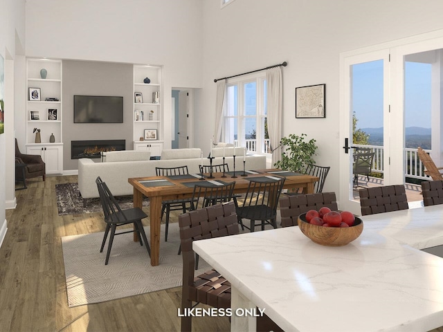 dining area featuring built in shelves, wood-type flooring, and a towering ceiling