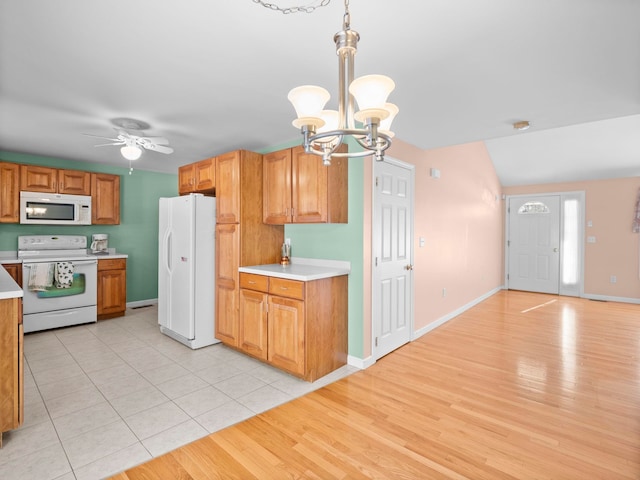 kitchen with hanging light fixtures, white appliances, ceiling fan with notable chandelier, and light tile patterned floors