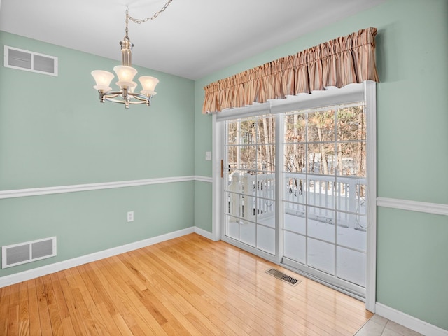 empty room with a notable chandelier and hardwood / wood-style floors