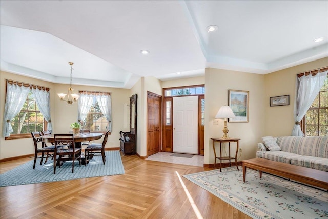 living room featuring a tray ceiling, light hardwood / wood-style flooring, and a notable chandelier