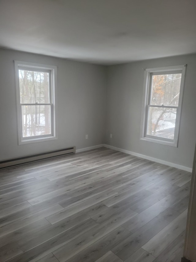 empty room featuring plenty of natural light, light hardwood / wood-style floors, and baseboard heating