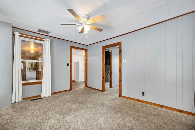 spare room featuring crown molding, ceiling fan, and light carpet