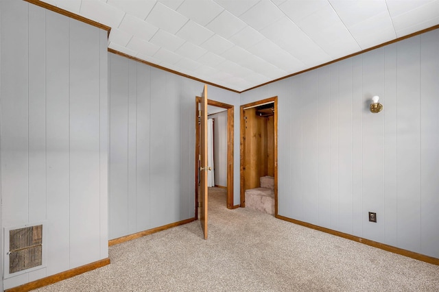 unfurnished room with ornamental molding and light colored carpet