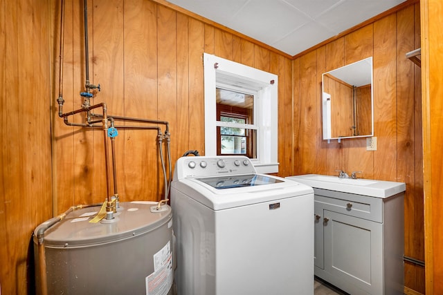 washroom featuring sink, water heater, cabinets, washer / clothes dryer, and wood walls